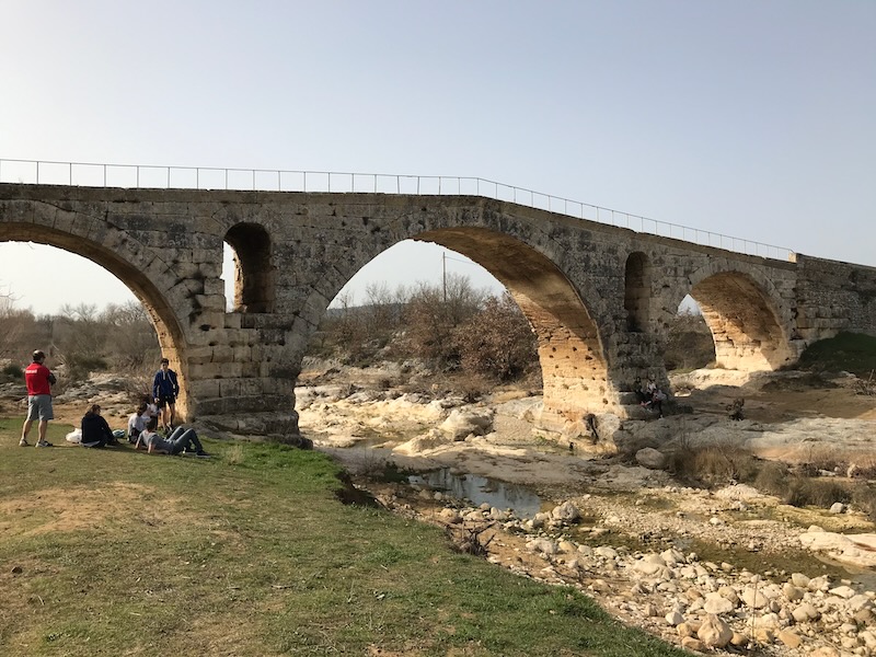 Cyclists relaxing next to the Roman Pont Julien near Bonnieux