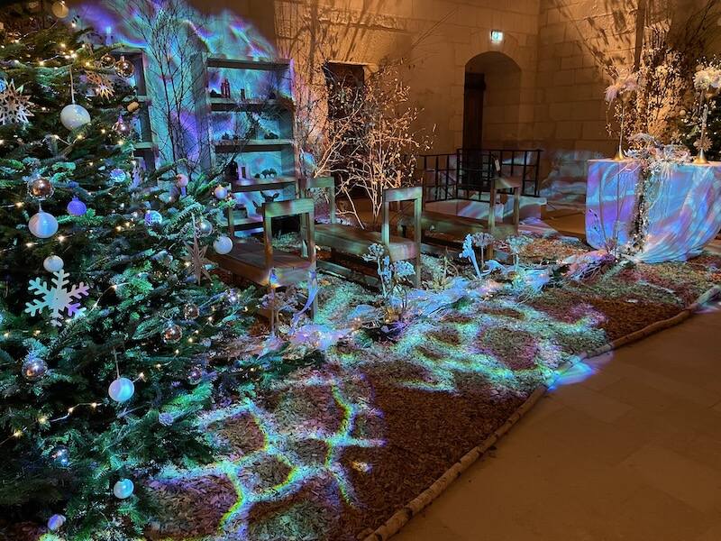 Benches and blue-green lights glowing in a room that was once used as a chapel in Chinon Fortress