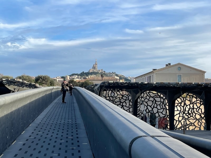 A close-up of the lattice-work of the Mucem in Marseille, with a view of the city beyond