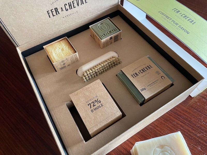 Gift box of Fer a Cheval soap from Marseilles, with beige and gree blocks of soap and a small brush.