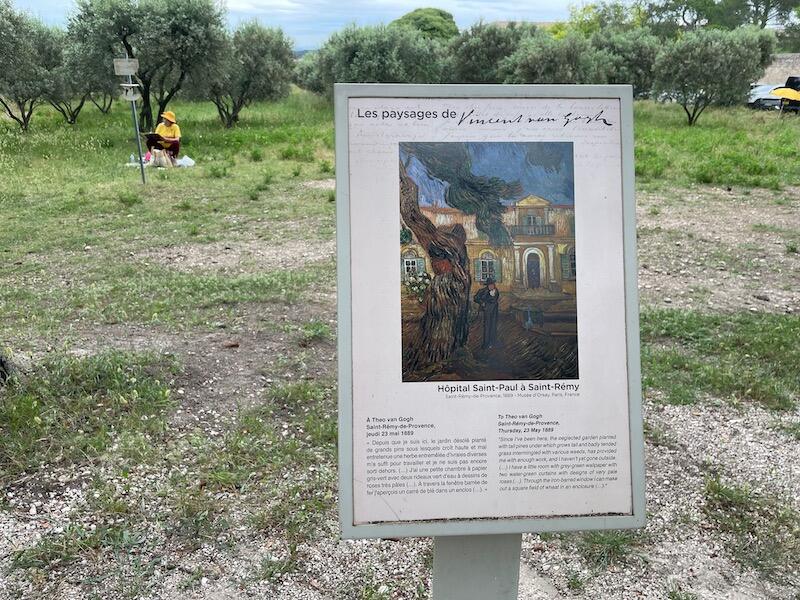 An artists paints near one of the panels depicting Van Gogh's art in Saint Remy de Provence